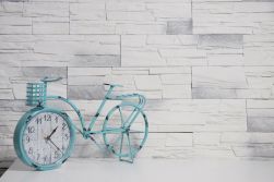 Ściana wyłożona kamieniem dekoracyjnym Castor Arctic z ozdobnym rowerem-zegarkiem w kolorze niebieskim