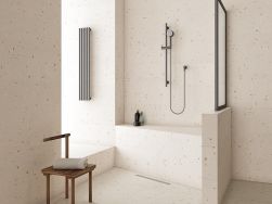 Łazienka wyłożona jasnymi płytkami lastryko Croccatne-R Tuttu Frutti z prysznicem i drewnianym krzesełkiem