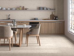Kuchnia wyłożona beżowymi płytkami lastryko Croccante-R Avellana z drewnianymi meblami, stołem i krzesłami