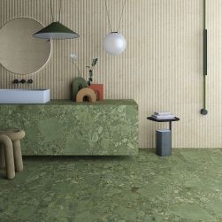 Łazienka wyłożona zielonymi płytkami imitującymi kamień Green Giada z umywalką nablatową, okrągłym lustrem, lampą wiszącą i ozdobami