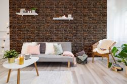 Przytulny salon z szarą kanapą i kolorowymi poduszkami, białym dywanem, jasnym stoliczkiem z ozdobami, wiklinowym fotelem i kamieniem dekoracyjnym Basalto Copper