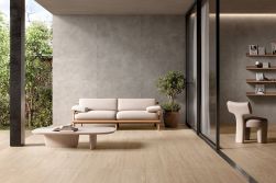 Taras ze ścianą wyłożoną szarymi płytkami imitującymi beton All Around Concrete Grey, z jasną kanapą i stolikiem