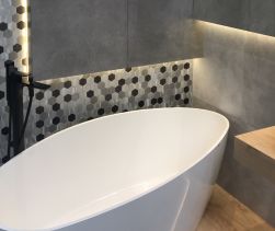 Ściana w łazience przy wannie wyłożona srebrną mozaiką Allumi Grey Hexagon Mix