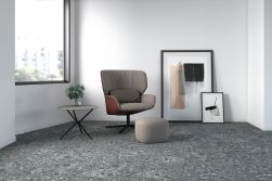 pomieszczenie wyłożone płytkami Clemon Graphite 60x120 z widocznym fotelem , obrazami , ławą pufem oraz rośliną ozdobną