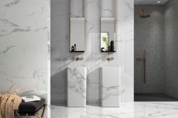 Elegancka łazienka wyłożona białymi płytkami imitującymi marmur z szarymi smugami z kolekcji Emigres Enzo z dwoma umywalkami stojącymi i dwoma podłużnymi lustrami oraz kabiną prysznicową we wnęce