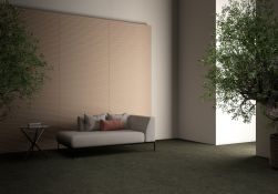 Pokój z zieloną podłogą i częścią ściany wyłożoną beżowymi płytkami 3D Tornares Nevada Greige, z szarą kanapą i stolikiem