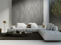 Salon ze ścianą wyłożoną płytkami 3D Tornares Olite Graphite z jasną kanapą narożnikiem i niskim stolikiem z ozdobami