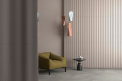 Pokój ze ścianami wyłożonymi beżowymi płytkami 3D Tornares RLV Zumaia Greige z fotelem i małym stoliczkiem