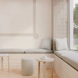 Przytulna restauracja ze ścianą wyłożoną białymi płytkami w połysku T Vapor Gloss, z poduszkami do siedzenia, małymi stolikami i pufą