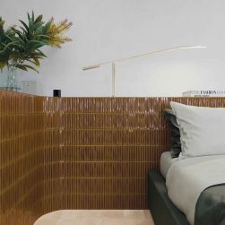 Sypialnia ze ścianami do połowy wyłożonymi brązowymi płytkami trójwymiarowymi Sweet Bars Honey Gloss z łóżkiem, rośliną w wazonie i złotą lampką