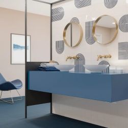 Łazienka z niebieską podłogą, fotelem, wiszącą półką z dwiema umywalkami nablatowymi i dowma okrągłymi lustrami oraz cegiełkami ściennymi dekoracyjnymi w połysku z reliefem Twist Vapor Titanium Blue Gloss