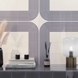 Ściana wyłożona dekoracyjnymi cegiełkami z reliefem w połysku Er Titanium Blue Gloss, z p&oacute;łką z książkami, lampką i ozdobami