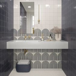 Łazienka z dwoma ścianami wyłożonymi granatowymi cegiełkami w połysku T Titanium Blue Gloss, z wiszącym blatem z umywalką i kosmetykami, lustrem oraz wiklinowym koszem