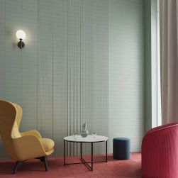 Pokój ze ścianą wyłożoną miętowymi płytkami TP Up Celadon Green Matt, z żółtym i różowym fotelem, pufą i małym stolikiem