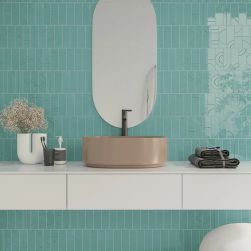 Ściana w łazience wyłożona błękitnymi cegiełkami w połysku ze wzorem Hammer Decor Aqua z białą półką wiszącą z beżową umywalką nablatową i owalnym lustrem