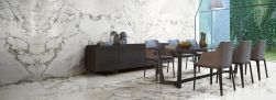 Jadalnia wyłożona płytkami imitującymi marmur Marmi Maxfine Arabescato, z długim stołem z krzesłami i komodą