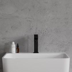 Widok od przodu na białą umywalkę z czarną baterią stojącą Omnires Baretti na tle jasnoszarej ściany