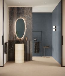 Łazienka z podłogą wyłożoną beżowymi płytkami imitującymi beton Balance Nude, z umywalką stojącą i owalnym lustrem