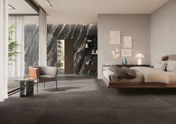 Sypialnia z czarnymi płytkami imitującymi beton Balance Umber na podłodze, z łóżkiem, fotelem i obrazami