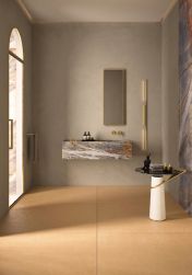 Łazienka z pomarańczowymi płytkami imitującymi beton Balance Ochre na podłodze, z umywalką ścienną, wąskim lustrem i małym stolikiem