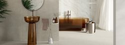 Łazienka z jasnymi płytkami imitującymi beton Balance Light Grey na podłodze, z wanną i umywalką wolnostojącymi z brązowego szkła