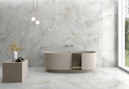 nowoczesna jasna łazienka, ładna wanna wolnostojąca, duże okno, stolik i na nim kwiaty, na podłodze i na ścianie płytki christy blanco