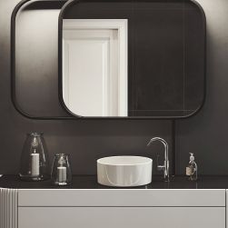 Ciemna, nowoczesna łazienka z szarą szafką, białą umywalką nablatową okrągłą i baterią umywalkową stojącą w chromie Massi Venice, z dużym lustrem i dwiema świeczkami