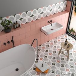 Widok z góry na łazienkę wyłożoną kolorowymi płytkami patchworkowymi z kolekcji Bauhome, z białą wanną wolnostojącą, baterią podtynkową i wylewką wolnostojącą, z białą umywalką wiszącą, ręcznikami i taboretem z kosmetykami