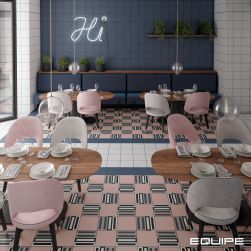 Restauracja wyłożona płytkami bazowymi i patchworkowymi z kolekcji Bauhome, z drewnianymi stołami z zastawą, białymi i różowymi fotelami, niebieską kanapą, kwiatami doniczkowymi i neonem na ścianie