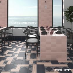 Restauracja z widokiem na ocean z podłogą wyłożoną granatowymi płytkami patchworkowymi z kolekcji Bauhome, ze stołami zabudowanymi różowymi cegiełkami z ciemną zastawą oraz grafitowymi krzesłami