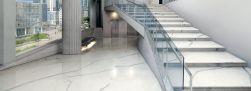 Przestronne pomieszczenie publiczne ze schodami wyłożone białymi płytkami imitującymi marmur Marmi Maxfine Bianco Venato Extra