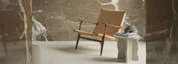 Ściany wyłożone brązowymi płytkami imitującymi marmur Marmi Maxfine Brown Fusion, krzesło i mały stolik