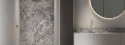Łazienka ze ścianą pod prysznicem wyłożoną szarymi płytkami imitującymi kamień Graniti Maxfine Celeste Aran, z białą szafką z umywalką i okrągłym lustrem