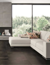 pomieszczenie wyłożone płytkami Claire Cemento 100x100 z dużą kanapą wolnostojącym oknem oraz elementami dekoracyjnymi