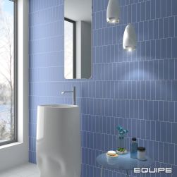 Łazienka ze ścianą wyłożoną niebieskimi cegiełkami matowymi Costa Nova Banyan Blue Matt z białą umywalką stojącą, lustrem i lampą wiszącą
