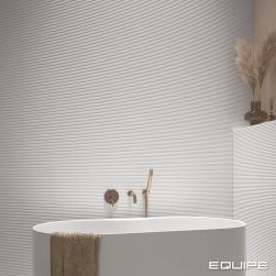 Ściany w łazience wyłożone białymi cegiełkami matowymi z reliefami Costa Nova Onda White Matt oraz biała wanna owalna