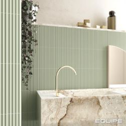 Łazienka wyłożona jasnozielonymi cegiełkami ściennymi matowymi z reliefami z kamienną umywalką w kolorze beżu i lustrem