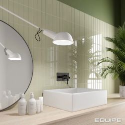 Ściana w łazience wyłożona w części jasnozielonymi cegiełkami w połysku Costa Nova Tansy Green Gloss z jasną, drewnianą szafką, umywalką nablatową, okrągłym lustrem i białą lampką