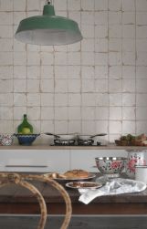 Fragment kuchni z widokiem na drewniany stół, białe meble, naczynia, lampę wiszącą i ścianę wyłożoną płytkami rustykalnymi FS Artisan-B 33x33