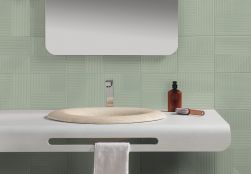 Biała półka wiszącą z kremową umywalką w łazience, z lustrem i białym ręcznikiem oraz miętowymi płytkami na ścianie z kolekcji Lins
