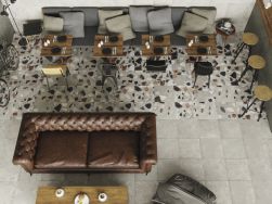 Restauracja z długą szarą kanapą, czterema kwadratowymi stolikami i krzesłami, brązową kanapą, barem i płytkami z kolecki FS Rialto