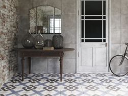 Pokój ze stolikiem, szklanymi wazami, lustrem, białymi drzwiami, rowerem i płytkami z kolekcji FS Sena