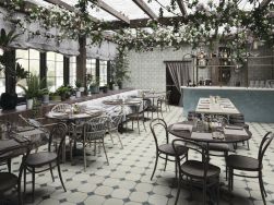 Restauracja ze stołami, stolikami, krzesłami, białą kanapą, barem, roślinami i płytkami z kolekcji FS Yard