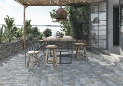 Kryty taras z drewnianym stołem, ławą, stołkami, kwiatami i płytkami z kolekcji FS Etna