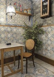 Kącik w restauracji z kwadratowym stolikiem, krzesłem, kwiatem, lampą wiszącą, ozdobami na ścianie i płytkami z kolekcji FS Roots