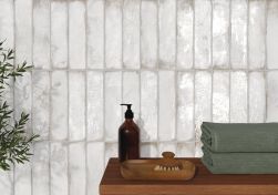 Widok na ciemny drewniany blat z dwoma zielonymi ręcznikami i dozownikiem oraz na ścianę wyłożoną cegiełkami z kolekcji Legacy