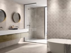 Łazienka wyłożona płytkami imitującymi beton Asphalt Mud z wanną, kabiną prysznicową, wiszącą półką z dwiema umywalkami i dwoma okrągłymi lustrami
