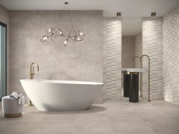 Minimalistyczna łazienka wyłożona płytkami imitującymi beton Asphalt Mud z białą wanną wolnostojącą, elegancką lampą wiszącą, pufą oraz umywalką stojącą