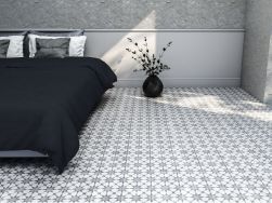 Minimalistyczna sypialnia z podwójnym łóżkiem z czarną pościelą i kwiatem w wazonie oraz szarymi płytkami w gwiazdki z kolekcji Cuban