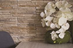 Ściana wyłożona kamieniem dekoracyjnym Davos Tierra z drewnianym stoliczkiem z wazonem z orchideą